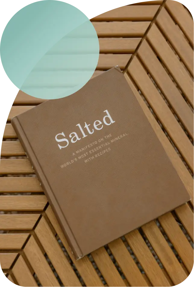 A hardcover book titled “Salted” resting on a wooden slat table.