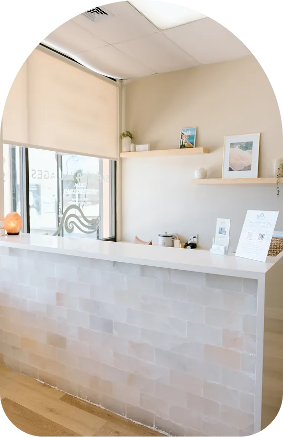 The reception area of Breathe Salt Rooms featuring a tan leather sofa, a large Himalayan salt lamp, and the company logo on the wall.