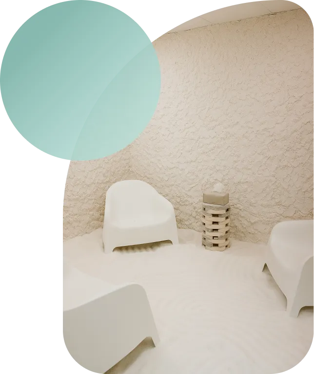 Calming salt therapy chair beside a warm, backlit salt wall at Breathe Salt Rooms.